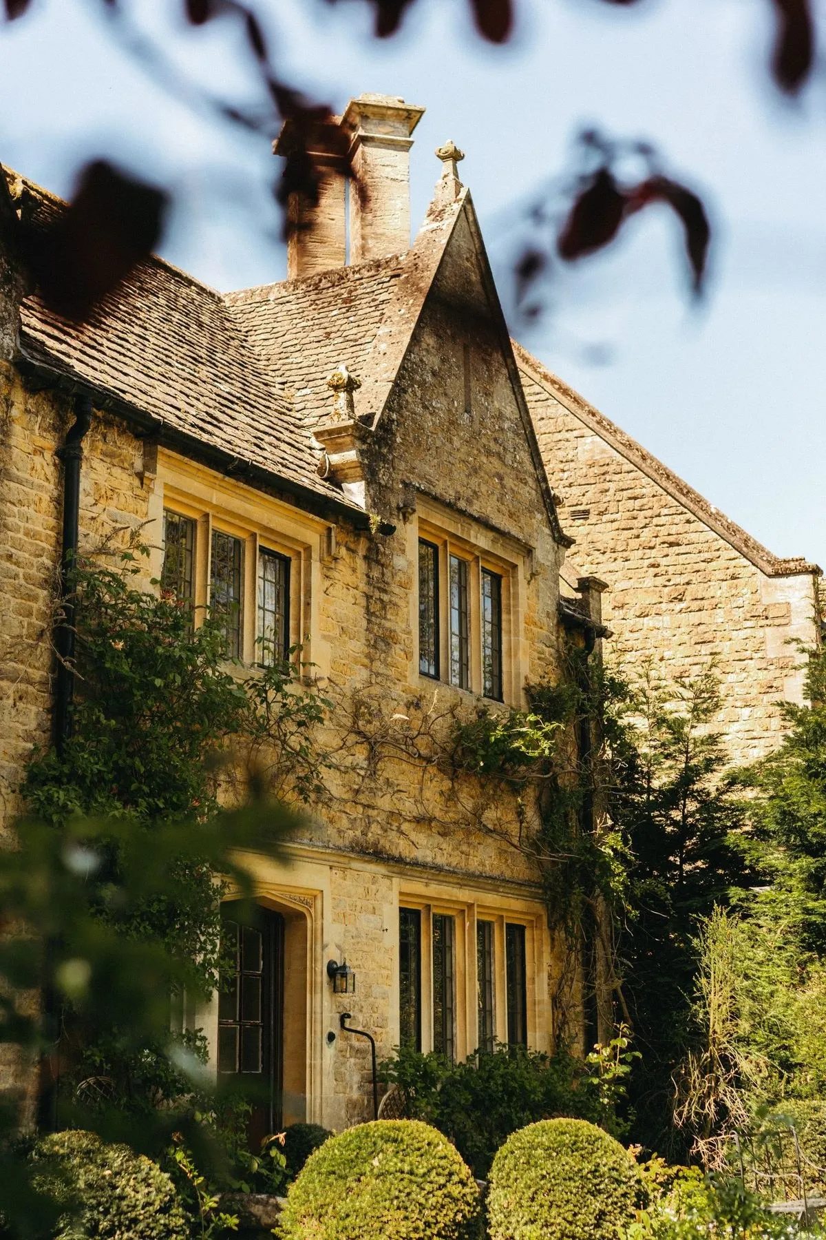 A Cotswold stone house framed by climbing plants